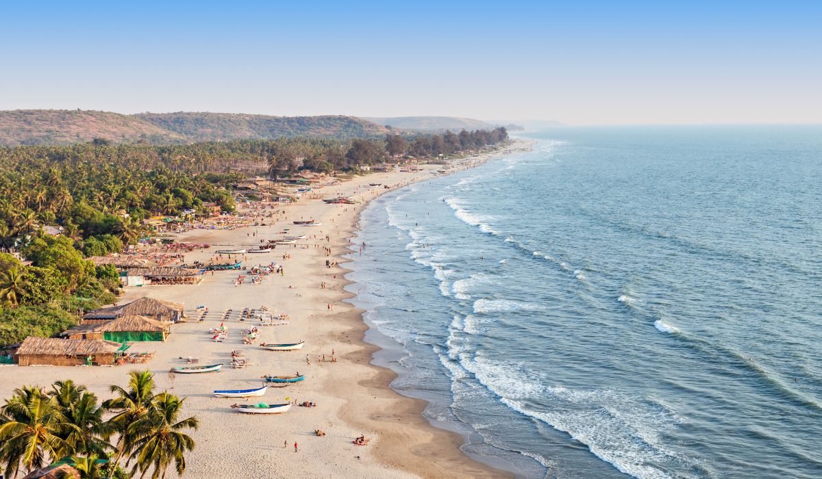 Aerial view of a crowded Goa beach with blue water and colorful boats, perfect for a 2026 Goa holiday package.