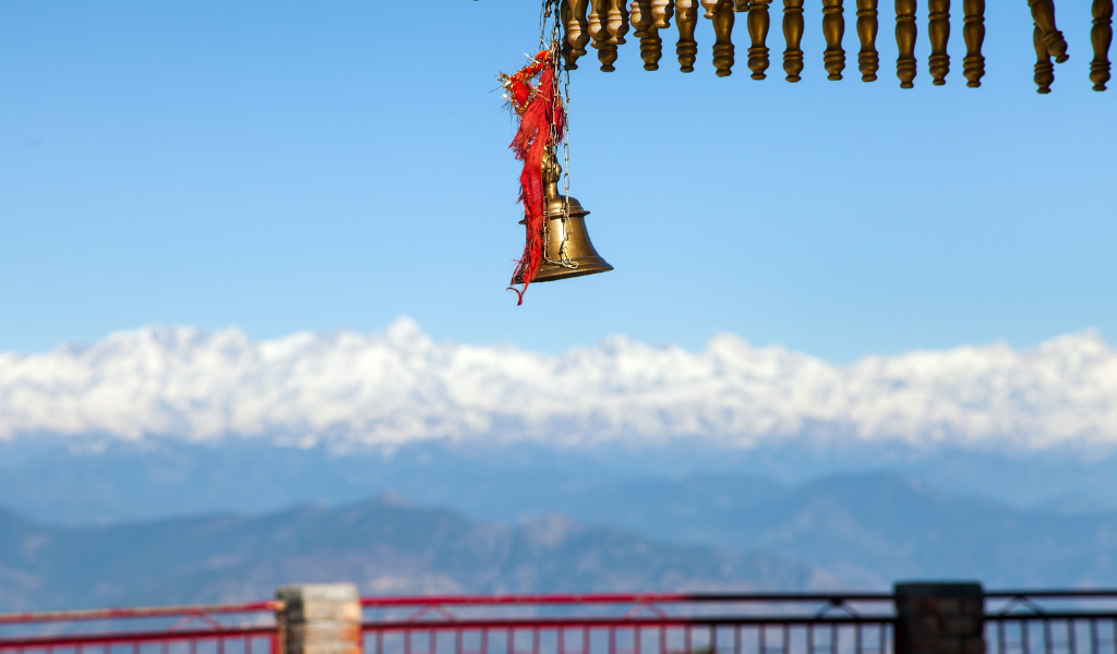 Traditional temple bell overlooking the scenic hills of kanatal