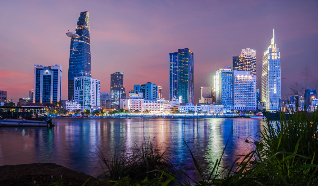 The vibrant night skyline of Ho Chi Minh City reflecting on the river, showcasing the luxury side of our vietnam tour packages from India