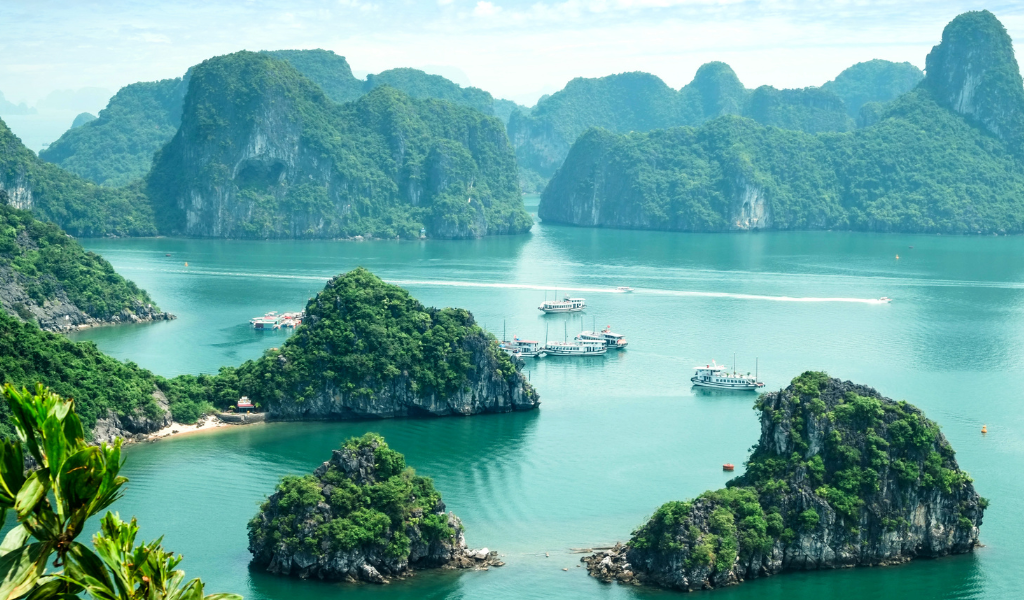 An emerald water view of Ha Long Bay with limestone islands and cruise boats, a major highlight of our Vietnam tour package and vietnam itineraries