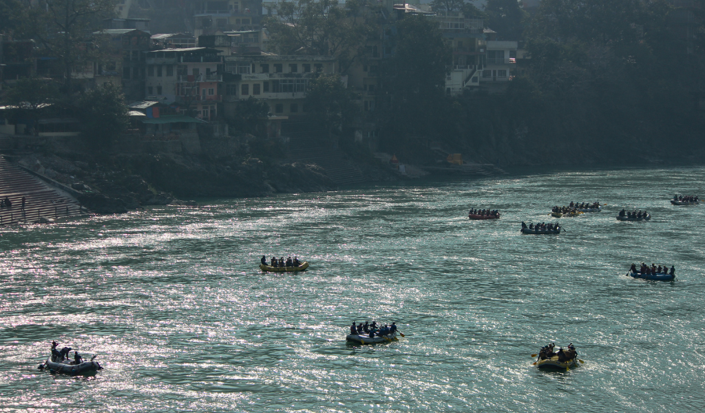 Travelers enjoying river rafting on the Ganga in Rishikesh, adding an adventure element to the luxury Ayodhya Varanasi Haridwar Rishikesh tour package.