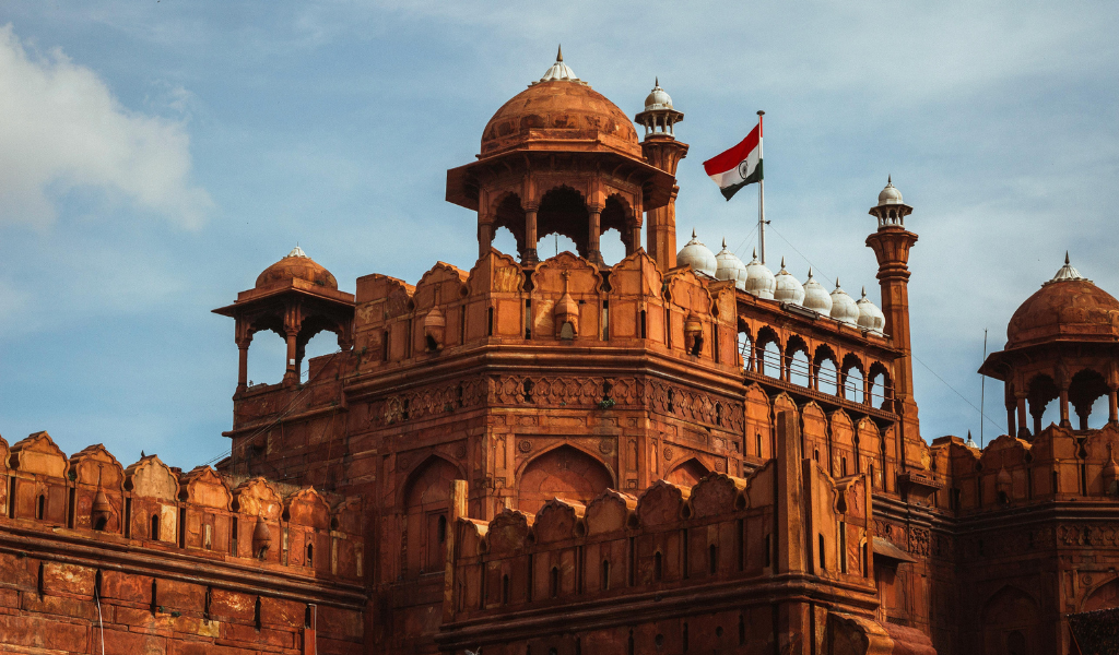 Close-up of the sandstone ramparts and domes of the Red Fort in Delhi with the Indian National Flag flying, visited during the Golden Triangle Tour part of the itinerary