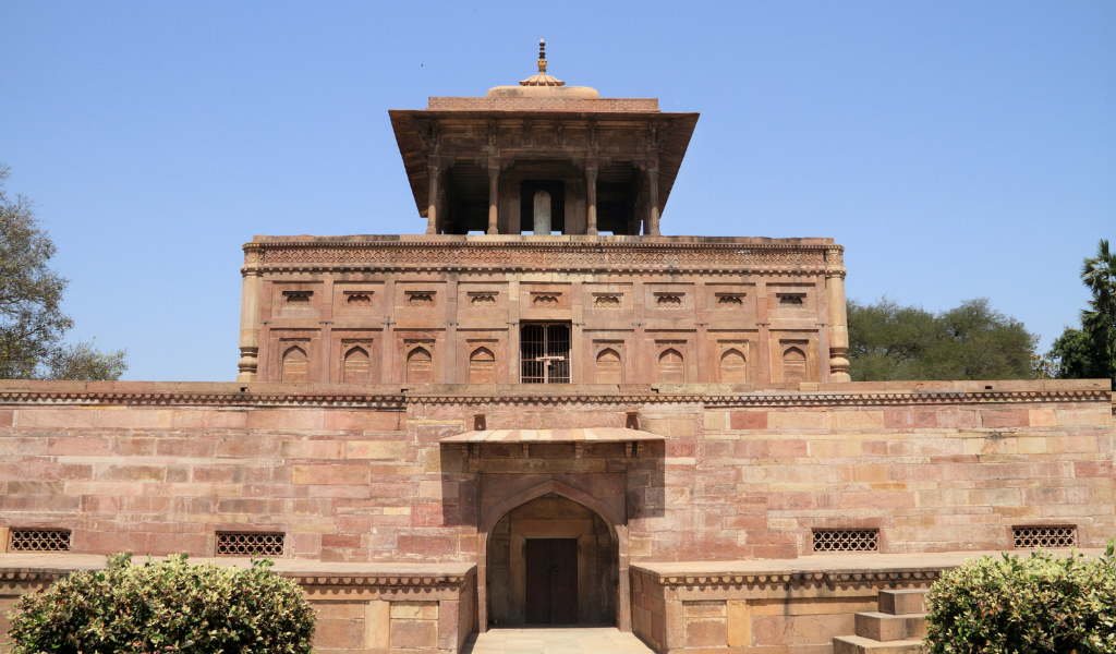 A unique multi-level stone heritage building under a clear blue sky, featured in our complete Allahabad tour package during Allahabad tour.