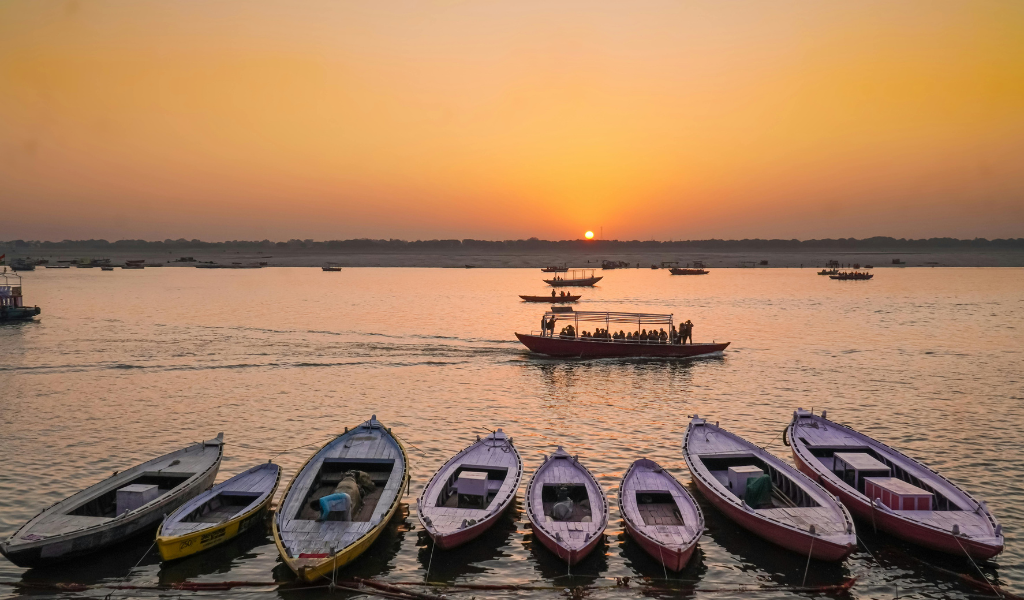 Traditional wooden boats on the River Ganga at sunset, offering a peaceful experience during the luxury Varanasi Ayodhya tour package.