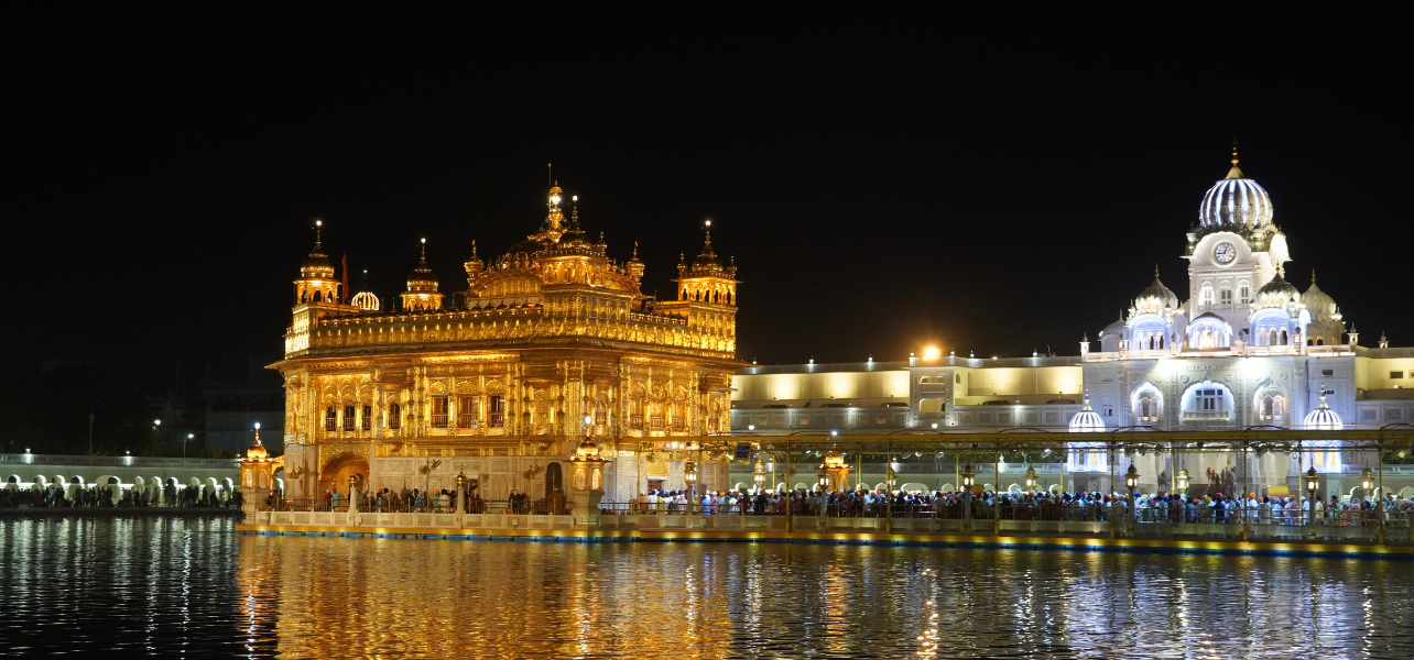 Golden Temple Amritsar Tour Package night view glowing with lights and reflection in water