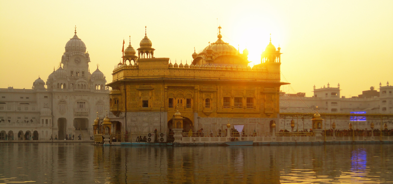 Golden Temple Amritsar Patial Tour Package at sunrise with reflection in holy water and Sikh pilgrims walking around the shrine