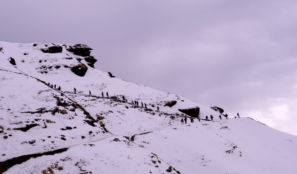 Trekkers walking along the snow-covered mountain route to Chandrashila Peak near Chopta Valley during their Auli Chopta Tour Package.