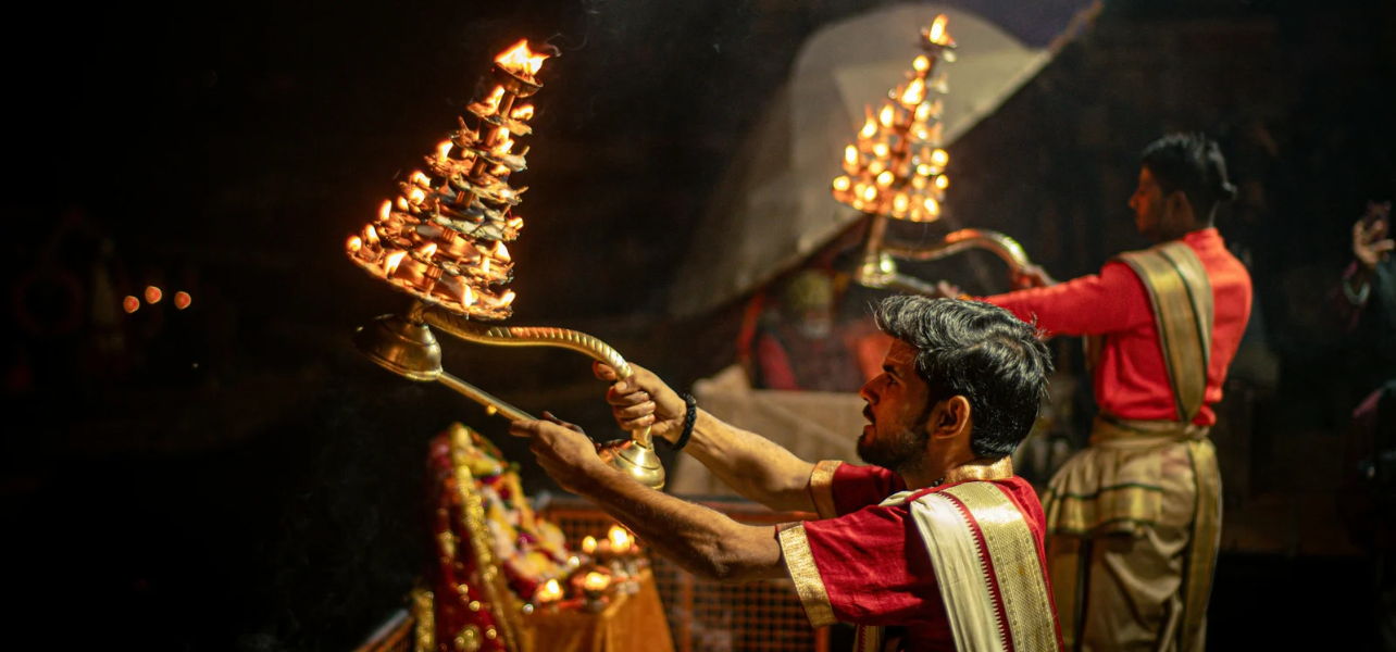 Hindu priests performing the grand evening Ganga Aarti with large brass multi-layered lamps at Dashashwamedh Ghat during a Varanasi tour package.