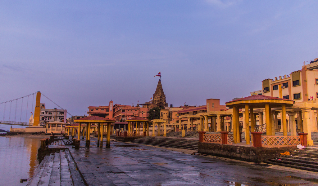 A peaceful evening view of the Dwarkadhish Temple and Sudama Setu bridge from the Gomti Ghat, a must-visit destination in any Dwarka Somnath tour package.