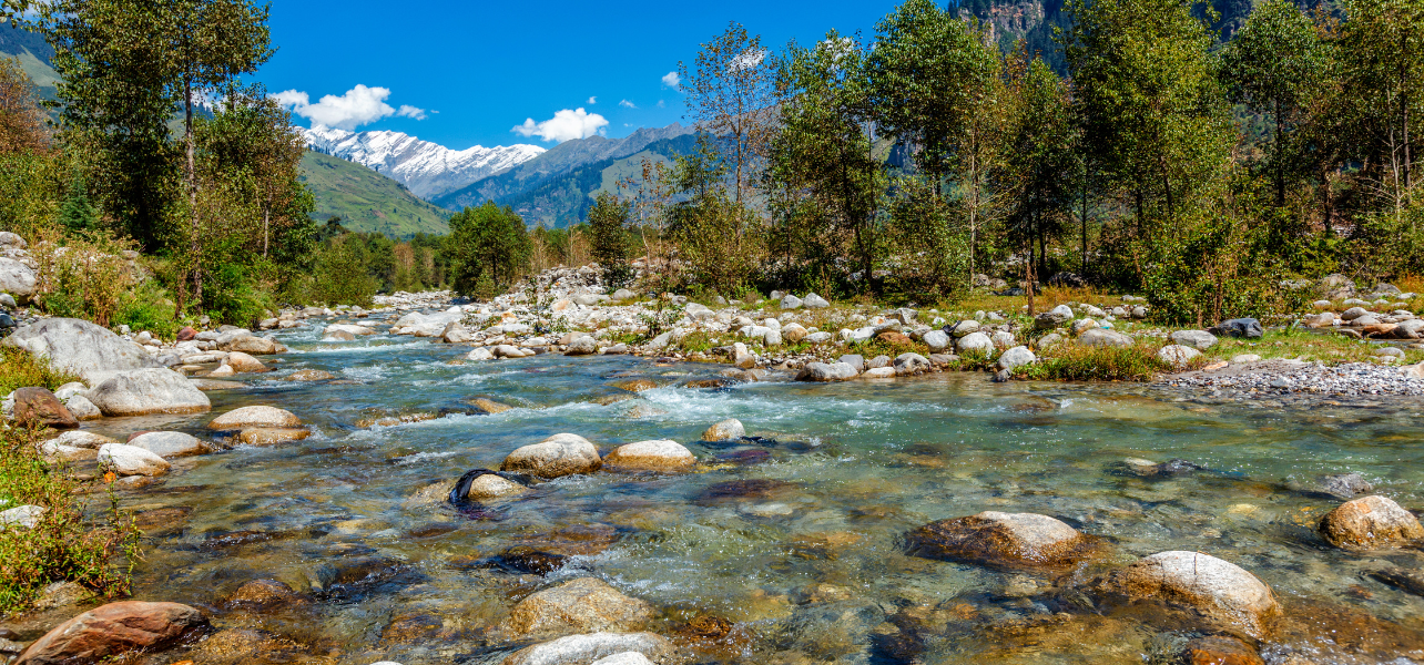 Kullu Tour Package crystal clear riverside landscape with snowy mountains in Himachal Pradesh