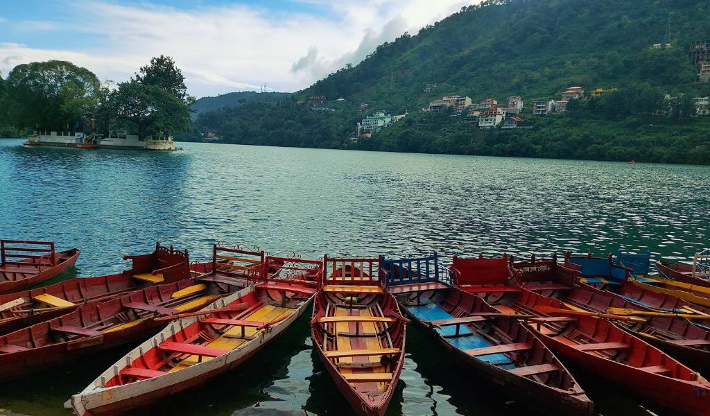 Colorful wooden boats parked at Naini Lake Nainital surrounded by green hills during Nainital sightseeing tour.