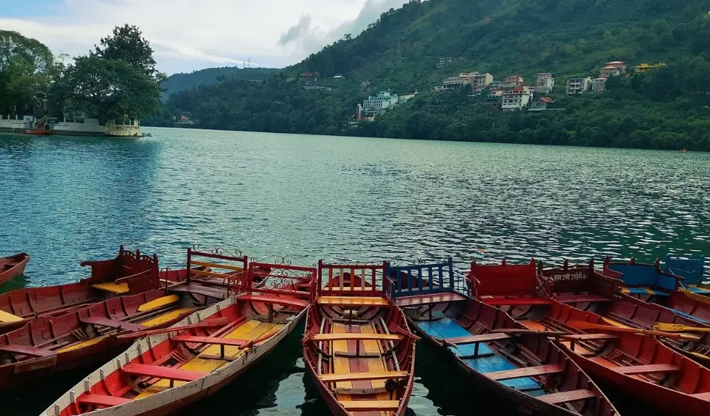 Nainital Tour Package featuring colourful boats at Naini Lake surrounded by lush green hills.
