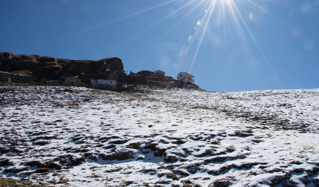Chopta tour package showing the snow-covered trail leading up toward Tungnath Temple under a bright blue sky.