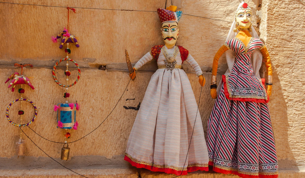 Colorful handmade Rajasthani male and female puppets displayed as authentic souvenirs on a Rajasthan package.